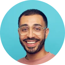 A smiling man with glasses against a blue background